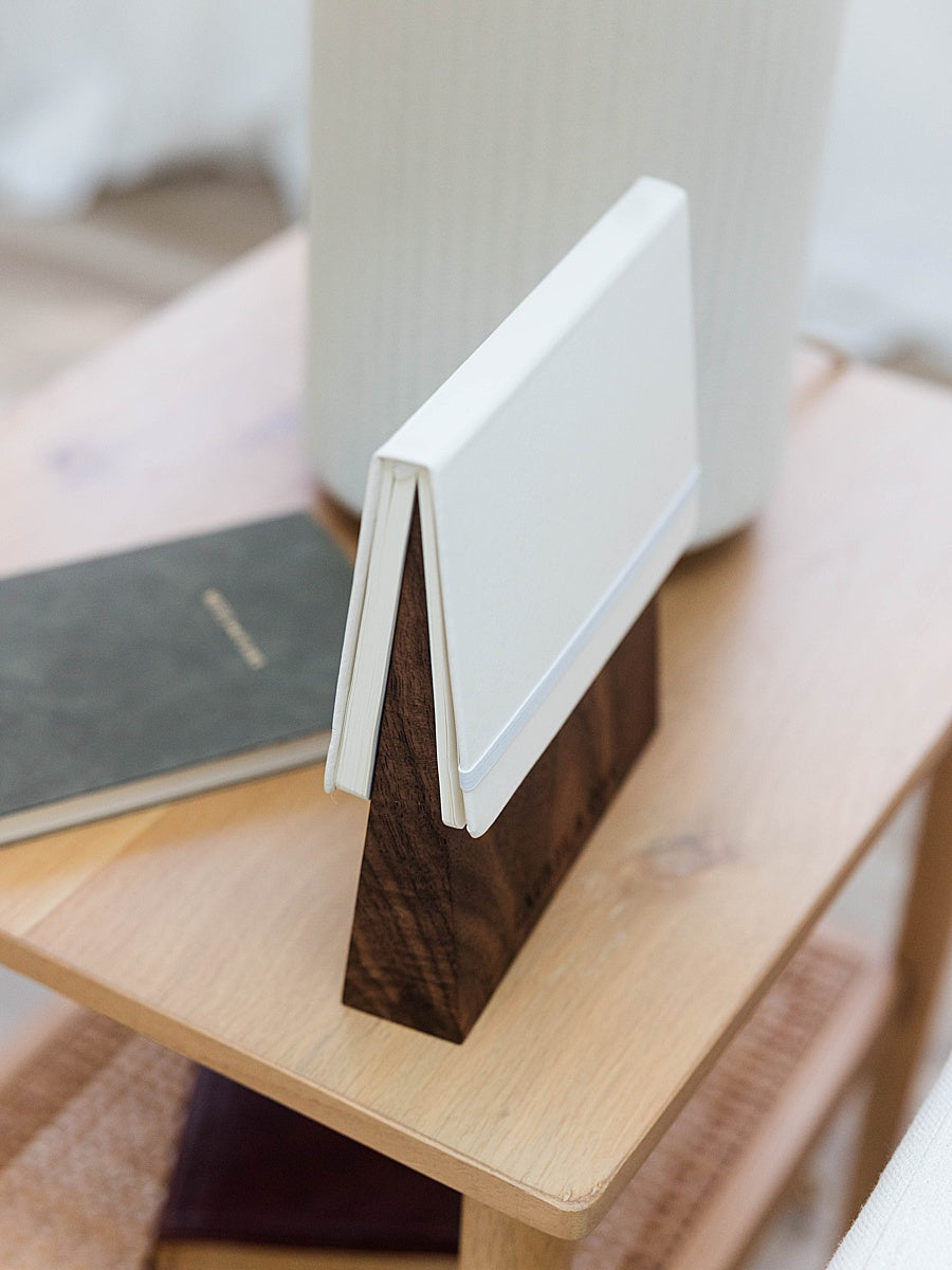 Solid walnut book wedge with white journal on top sitting on a side table