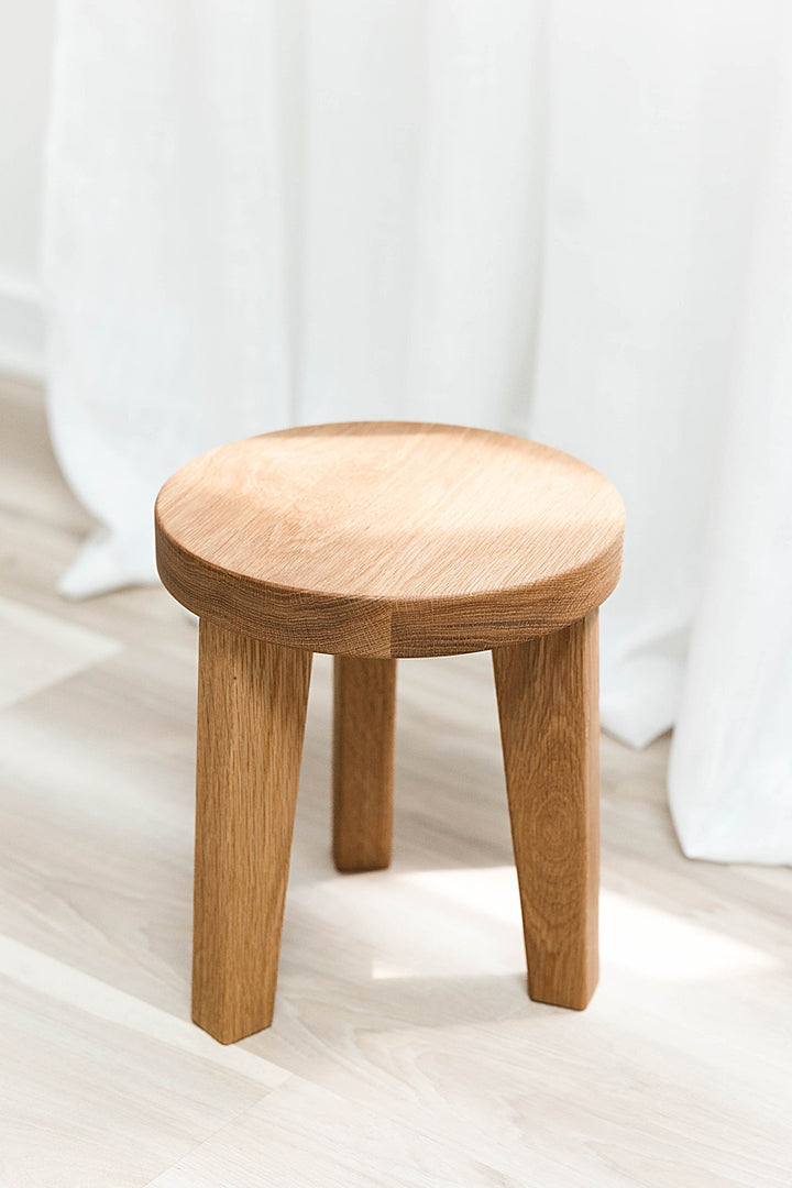 Solid white oak stool with a round top and three legs on a light background