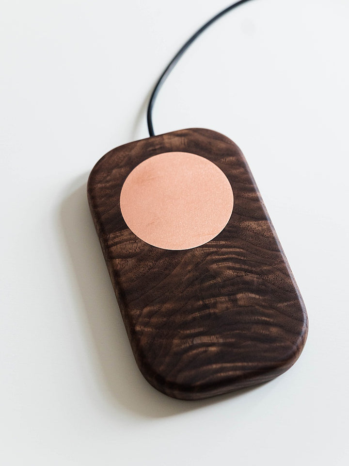Walnut grounding board board with a circular copper component and black cable on a white background