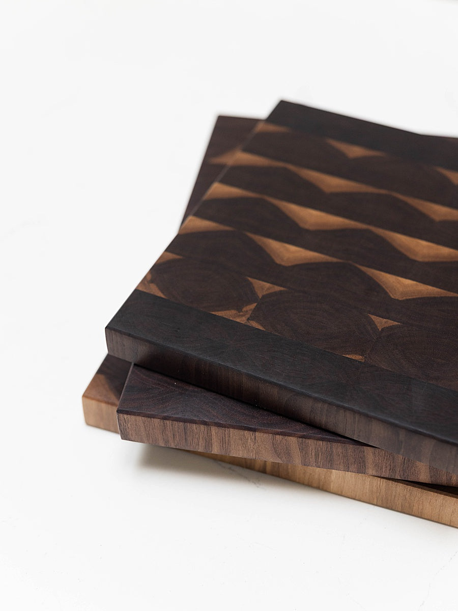 Stack of walnut end grain cutting boards on a white background